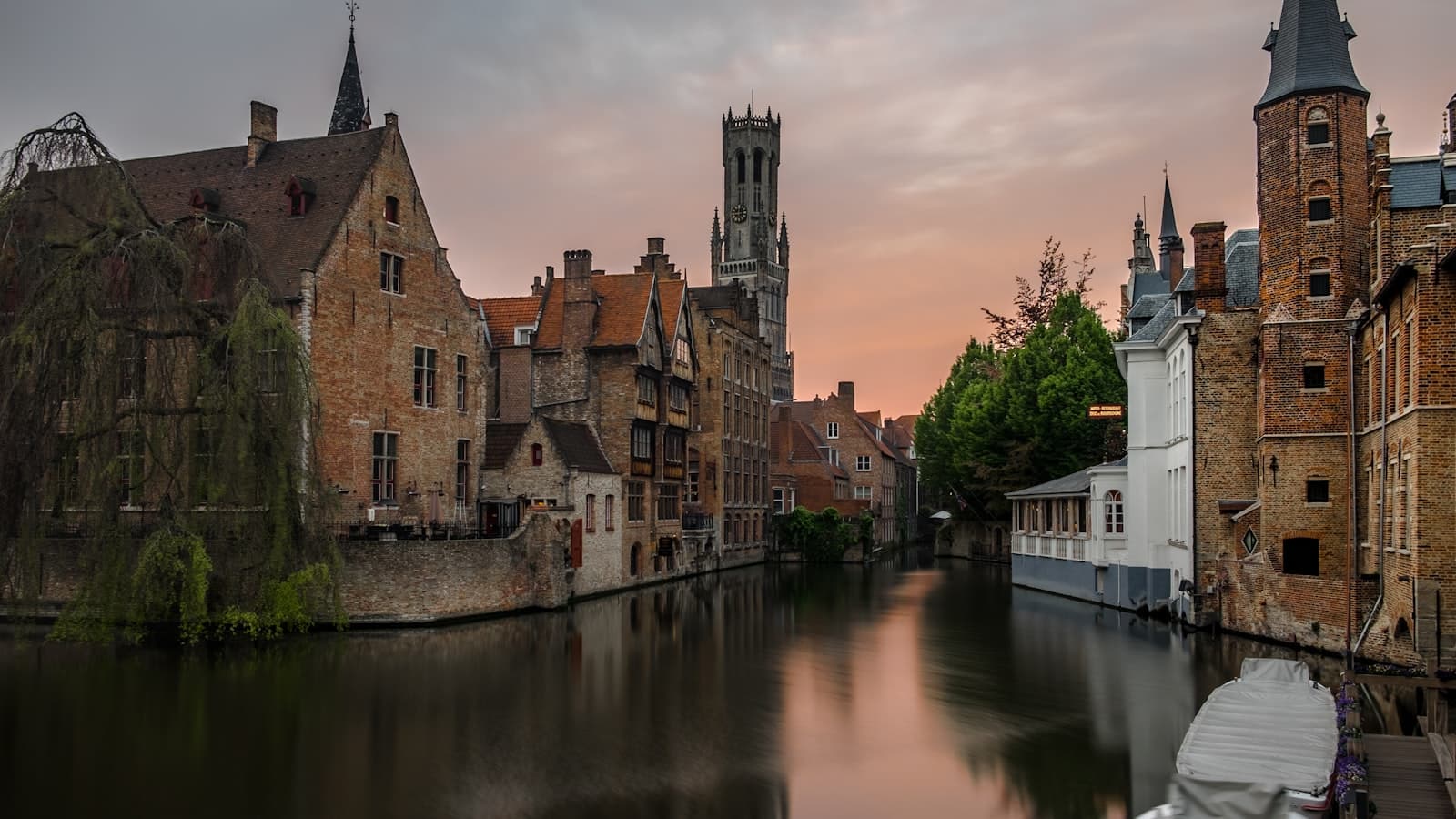Bruges' Rozenhoedkaai canal and medieval belfry at dusk