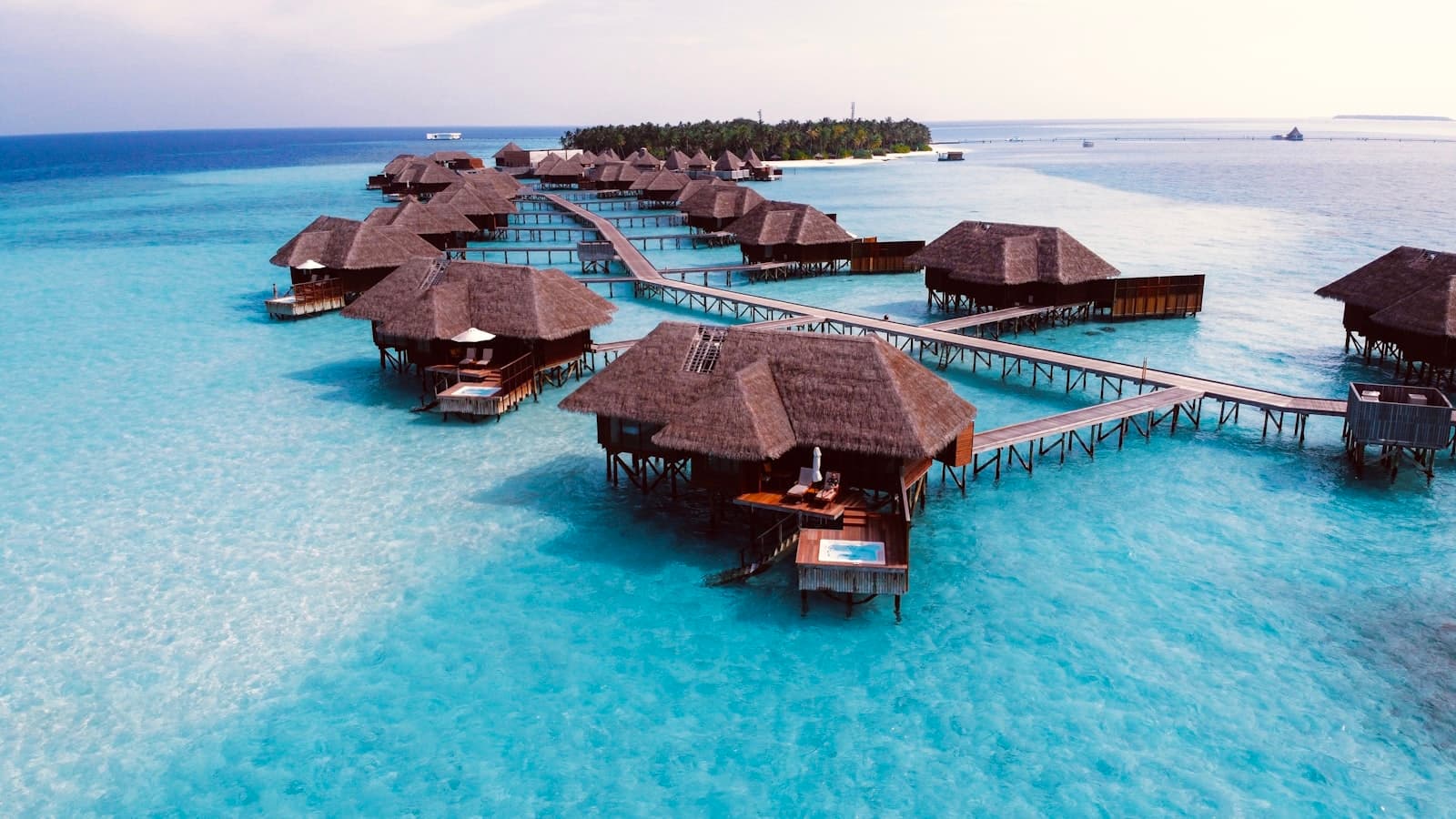 Aerial view of thatched overwater villas and boardwalks in a turquoise Maldives lagoon