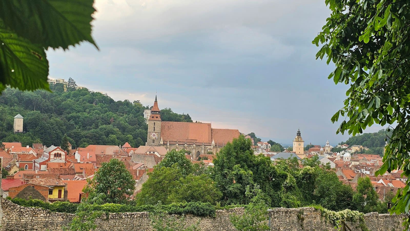 The Black Church rising above the red-tiled roofs of Brașov's old town, framed by forested hills