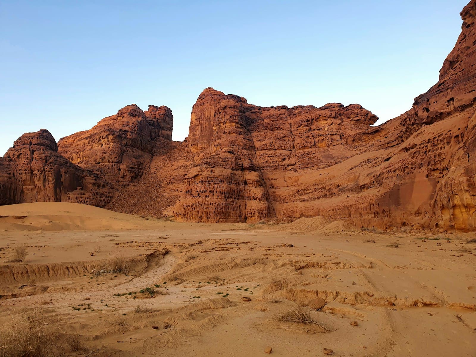 Red sandstone cliffs rising from the desert sands of AlUla, Saudi Arabia