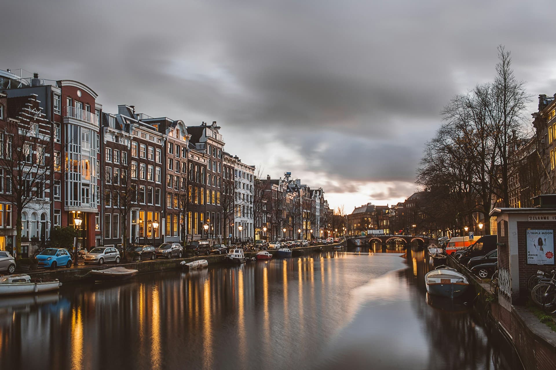 Traditional Dutch canal houses along an Amsterdam canal with bicycles on the bridge