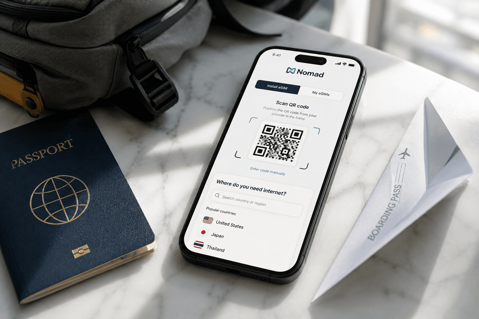 Smartphone showing the Nomad eSIM app next to a passport and travel backpack on a marble surface