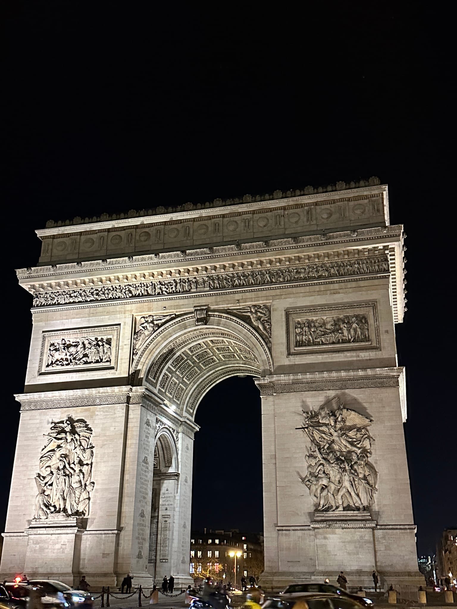 Arc de Triomphe illuminated at night showing the detailed relief sculptures, Paris