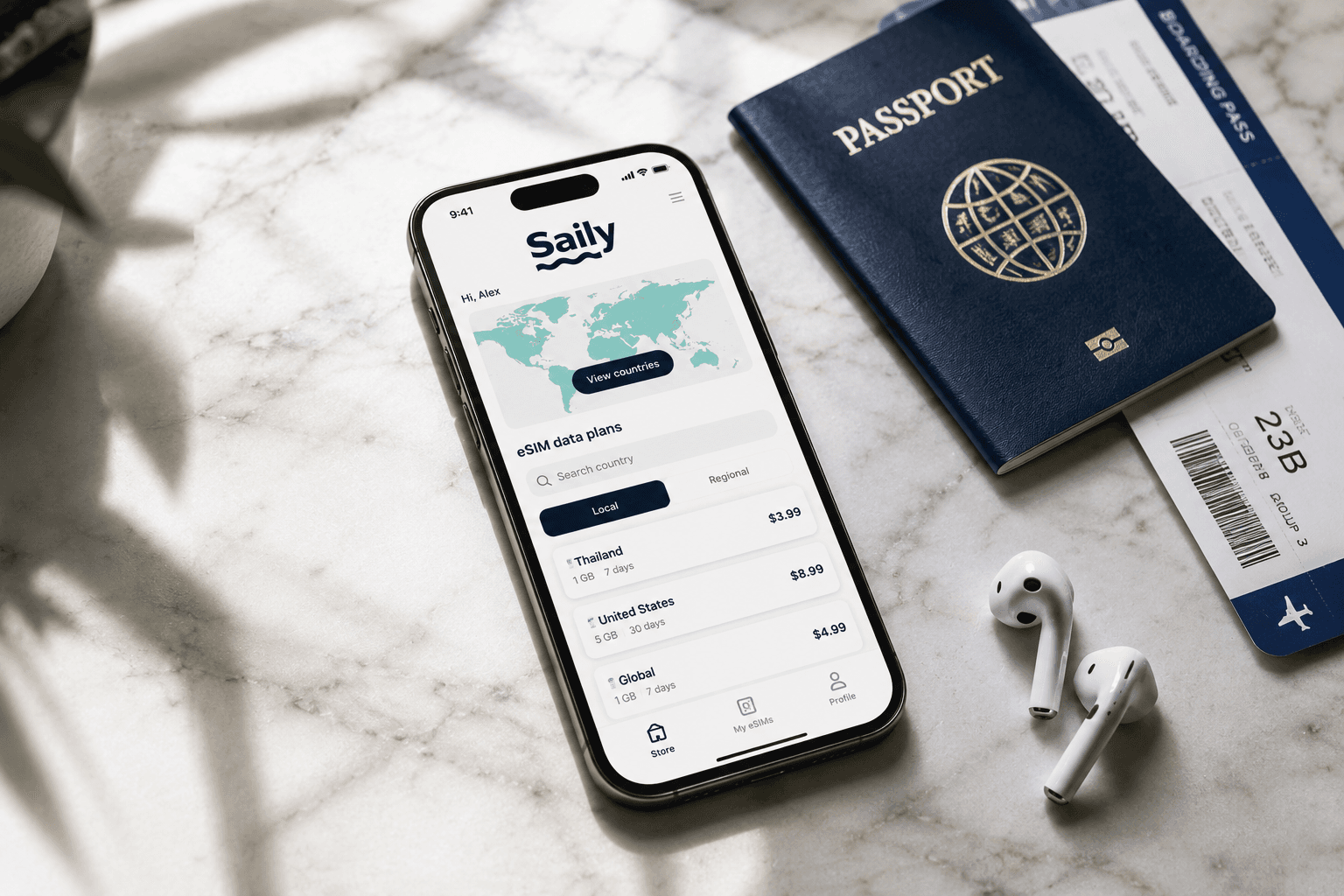 Smartphone showing the Saily eSIM app next to a passport and earbuds on a marble surface